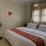 Double bedroom with woven runner and African art, JOSIRE Residence
